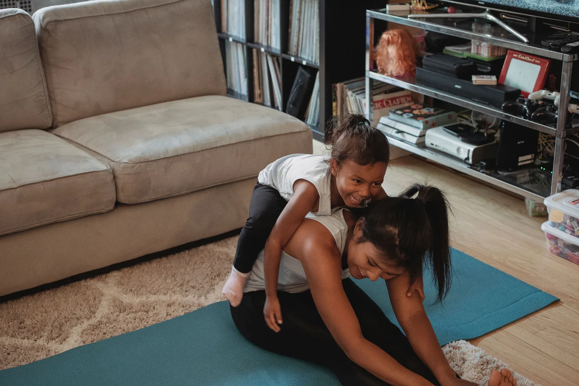 Moeder rekt uit op yogamat, dochter ligt op haar rug