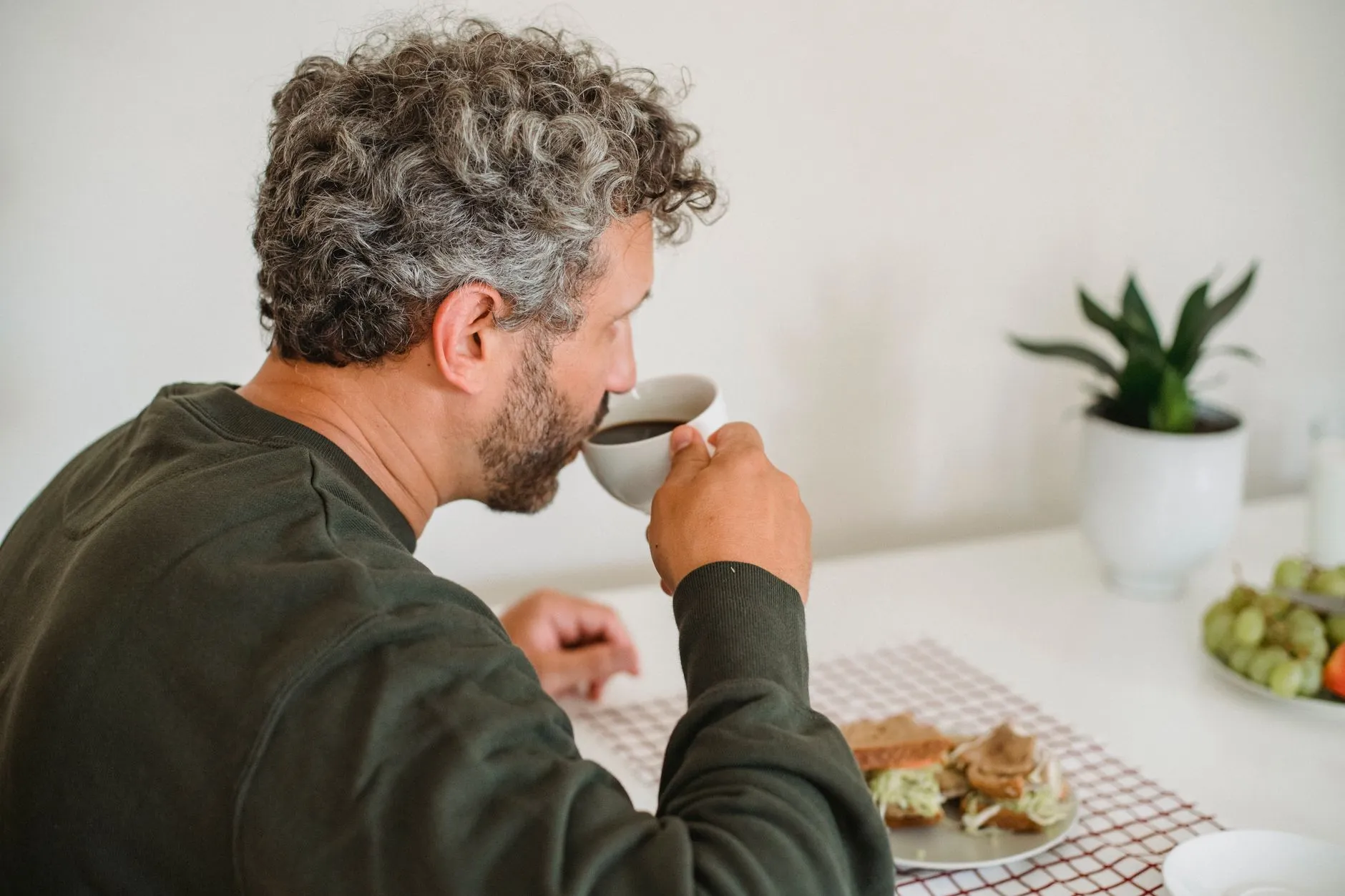 Man drinkt 's ochtends rustig koffie aan de ontbijttafel
