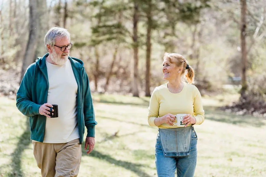 Man en vrouw van middelbare leeftijd wandelen samen buiten met een kop koffie