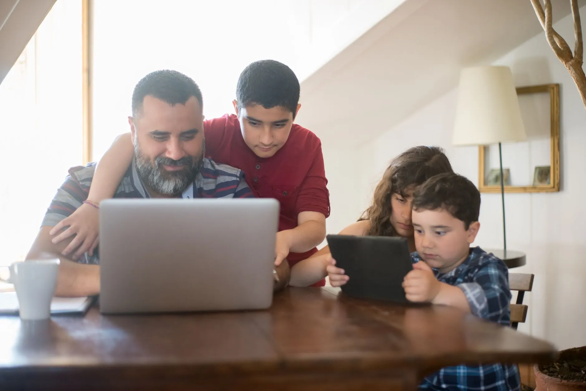 Vader en kinderen samen achter tablet en laptop: schermtijd bij kinderen