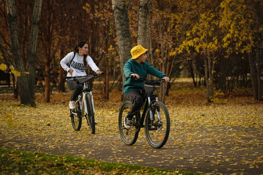 Kind fietst met een ouder door het herfstpark: kinderen bewegen te weinig