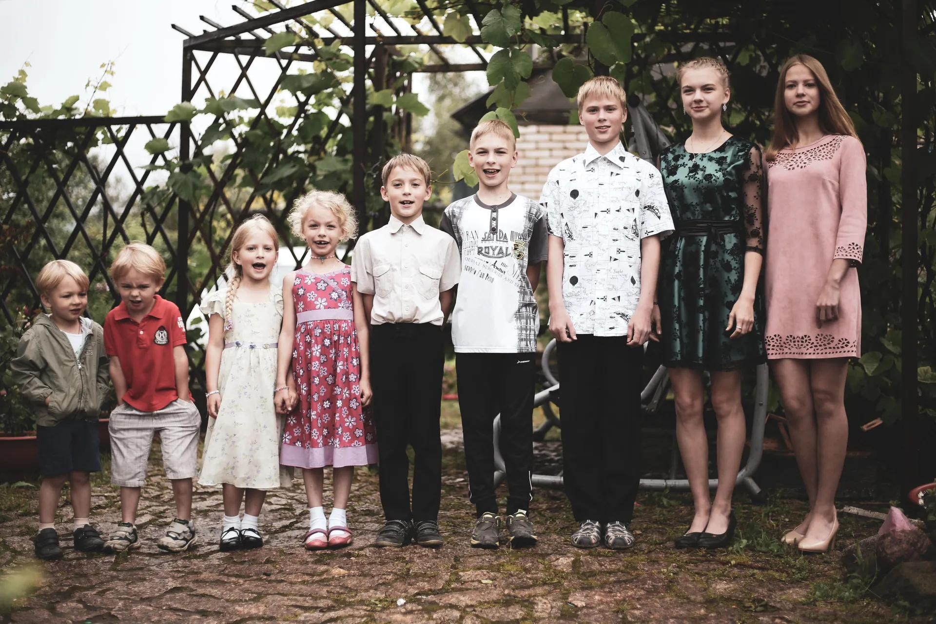 negen kinderen van peuter tot puber naast elkaar in een tuin