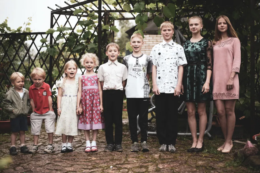 negen kinderen van peuter tot puber naast elkaar in een tuin