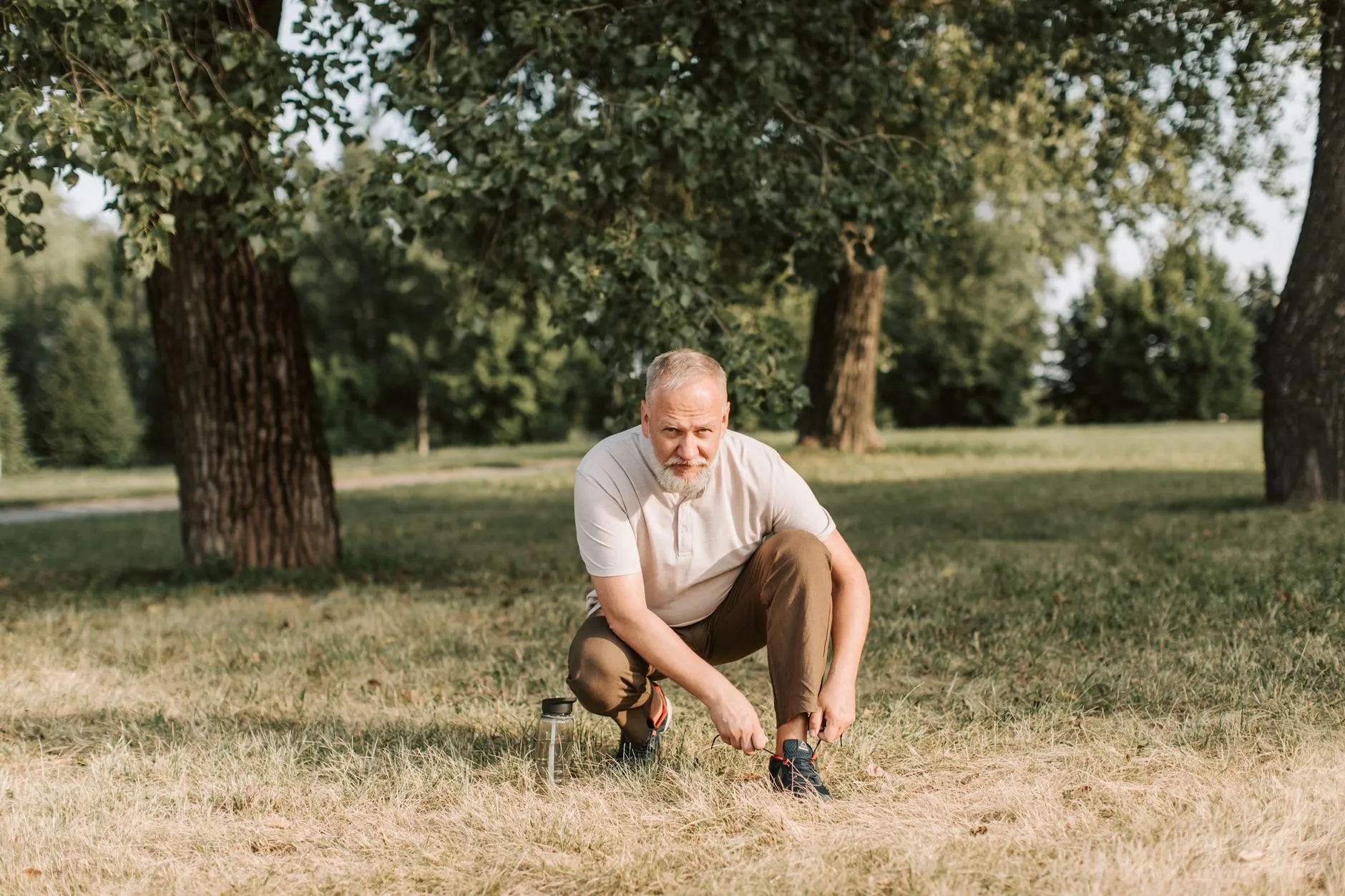 Oudere man strikt zijn veters in een park, klaar om te gaan wandelen