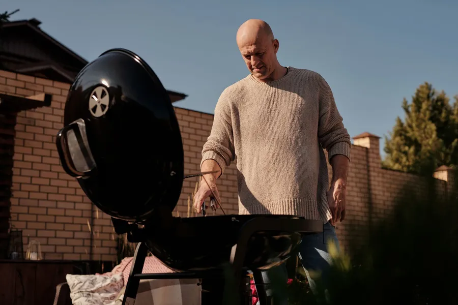 Man bakt vis op de barbecue in zijn eigen tuin
