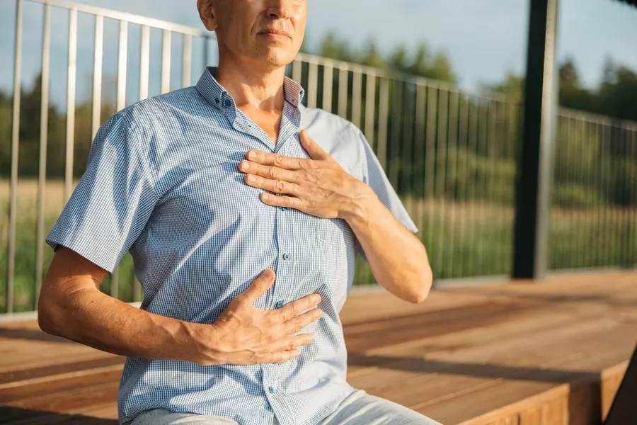 Man legt zijn handen op zijn borst en buik tijdens een ademoefening