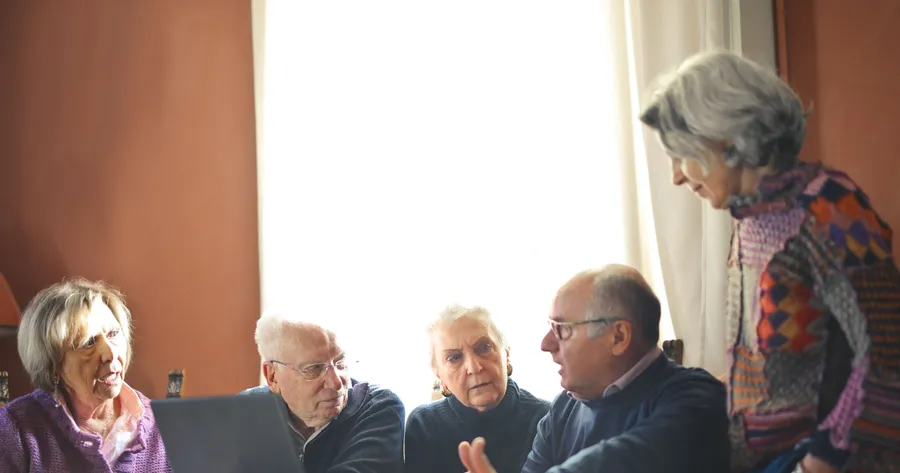 Ouderen in gesprek rond een tafel met een laptop