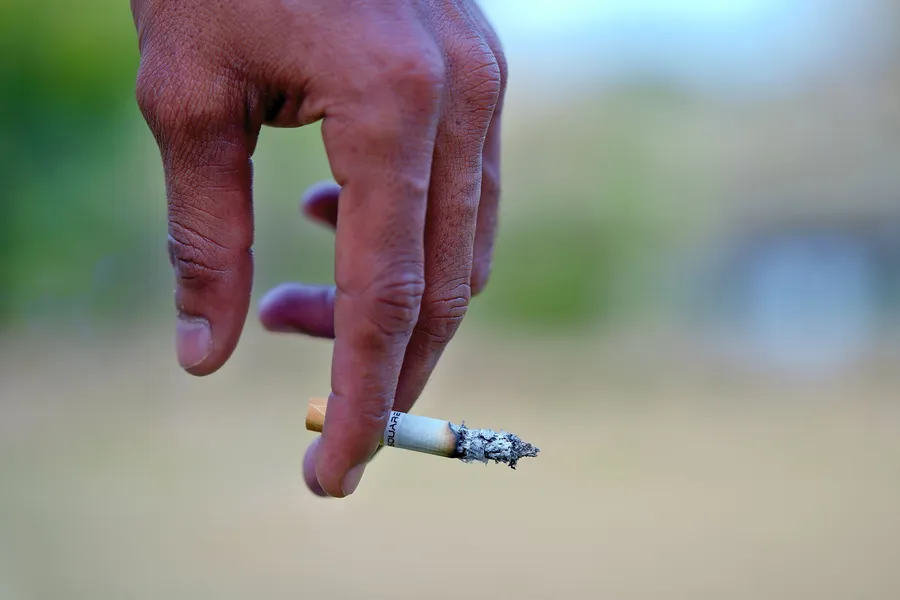 Hand houdt een brandende sigaret vast