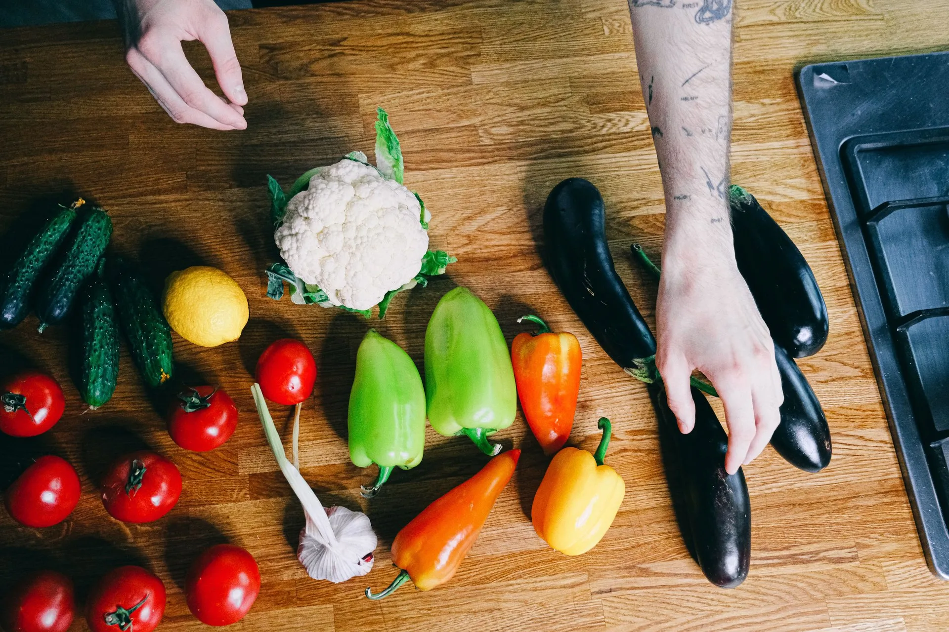 Handen leggen verschillende groenten op een keukentafel