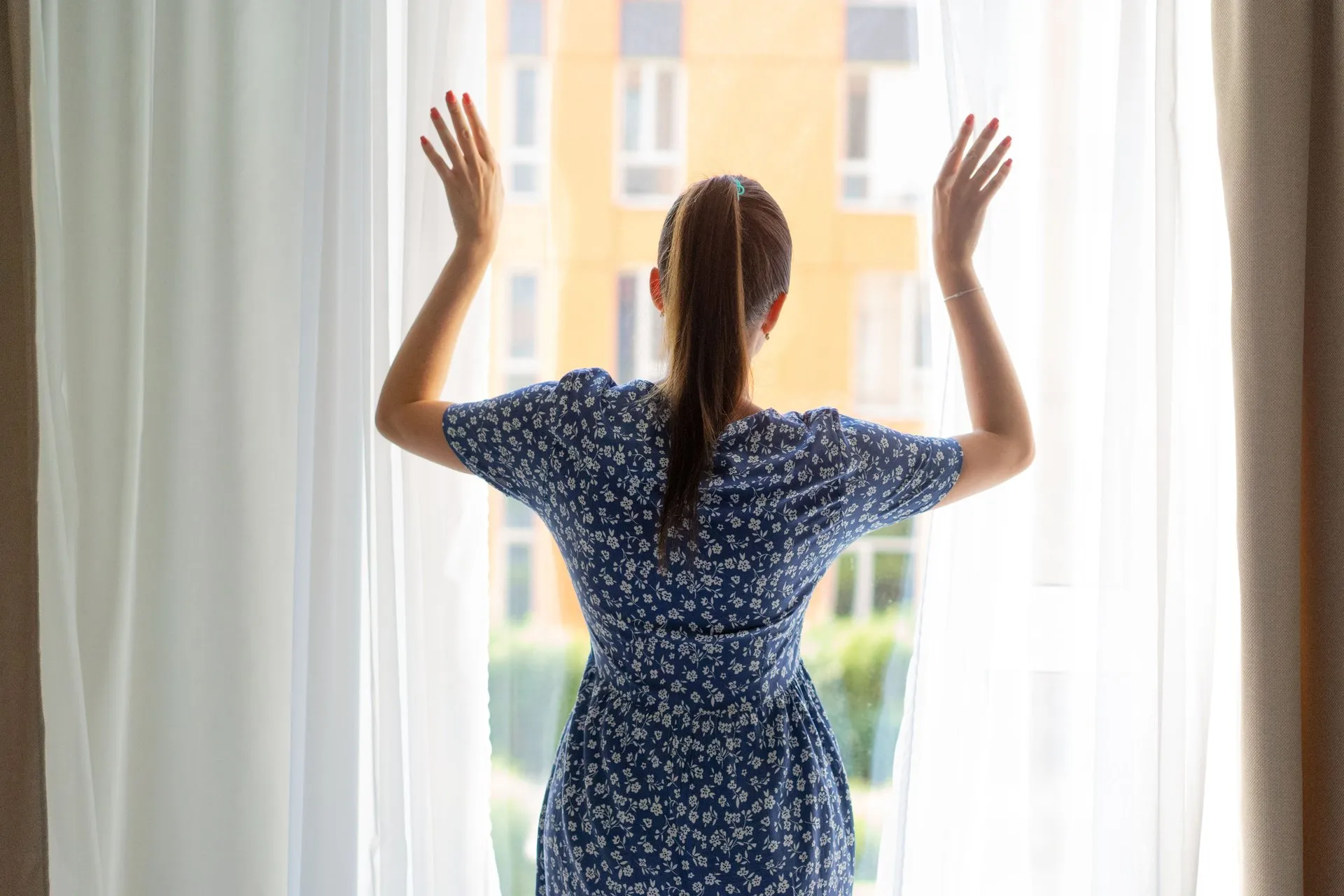 Vrouw opent de gordijnen bij een raam