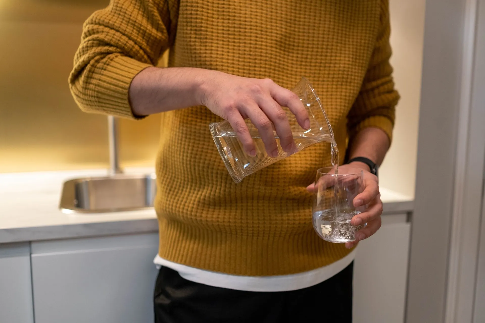 Man schenkt water uit een karaf in een glas