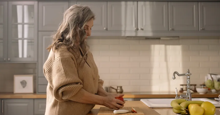 Vrouw met een appel aan het aanrecht