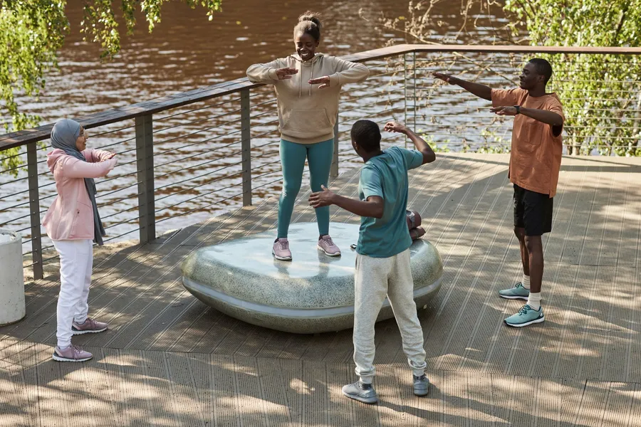 Vier volwassenen doen samen oefeningen op een vlonder aan het water