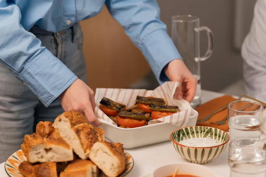 Vrouw zet een schaal met gegrilde groenten op tafel