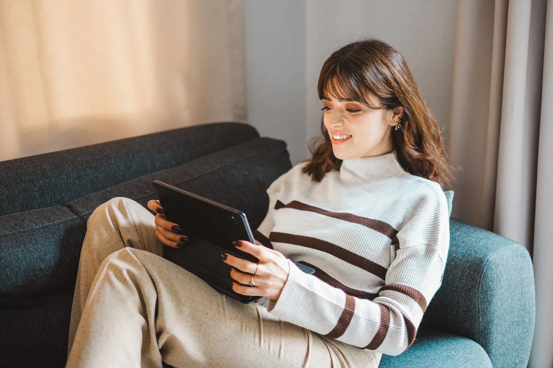 Vrouw zit ontspannen met een tablet op de bank