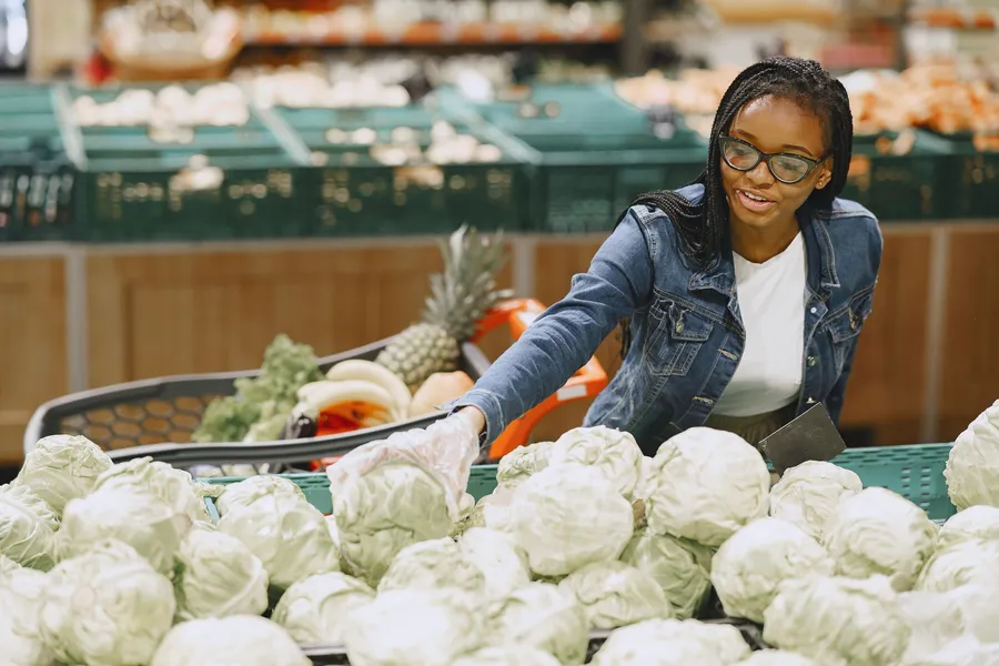 Vrouw kiest een kool in de supermarkt
