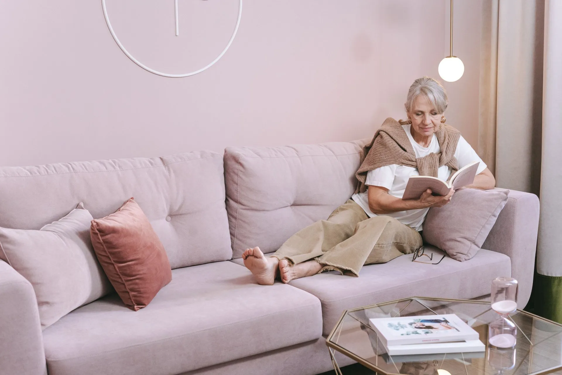 Oudere vrouw leest een boek op de bank