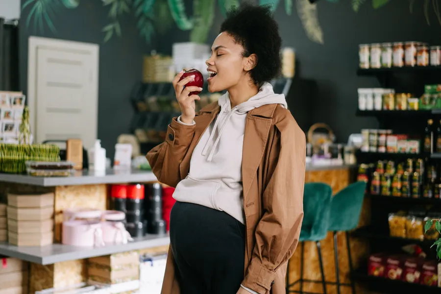 Zwangere vrouw neemt een hap van een appel