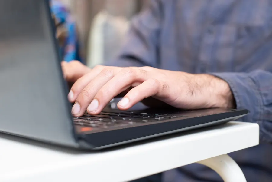 Handen typen op het toetsenbord van een laptop