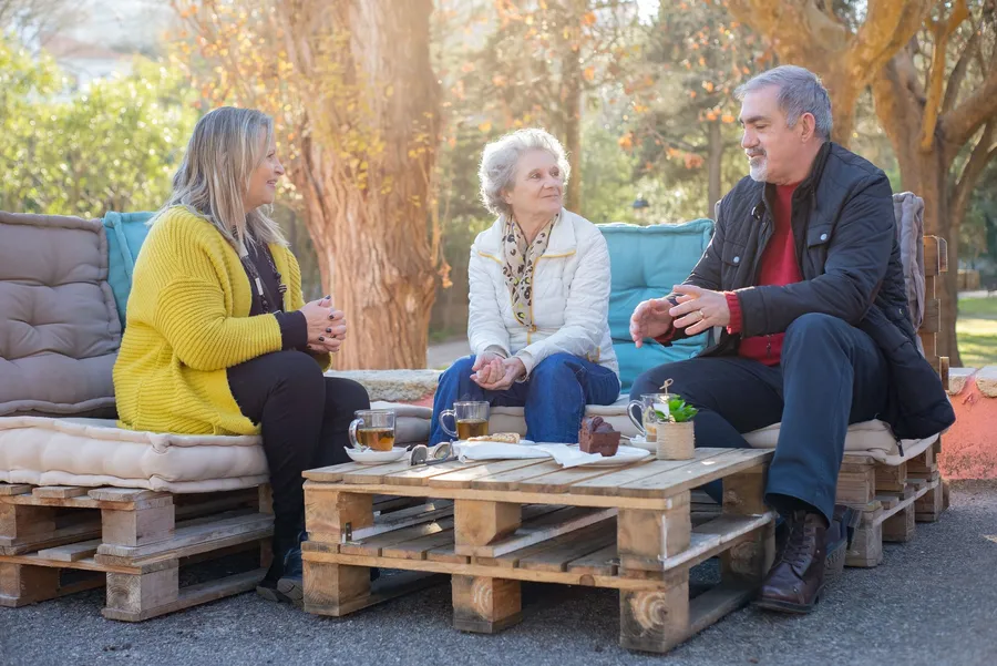 Drie oudere volwassenen praten buiten bij een tafel