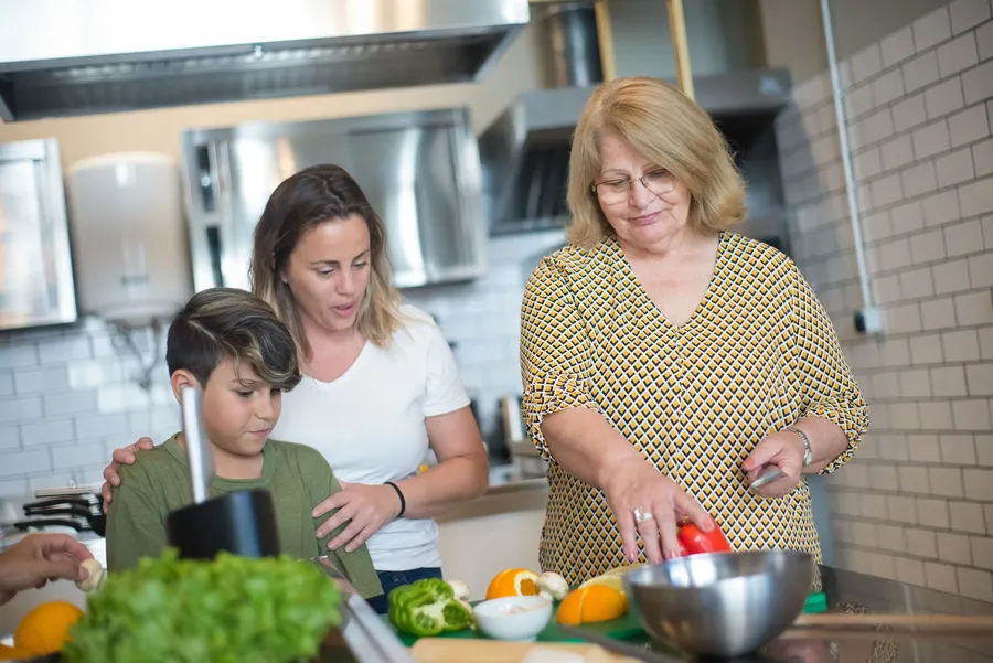 Twee vrouwen en een kind bereiden groenten in de keuken
