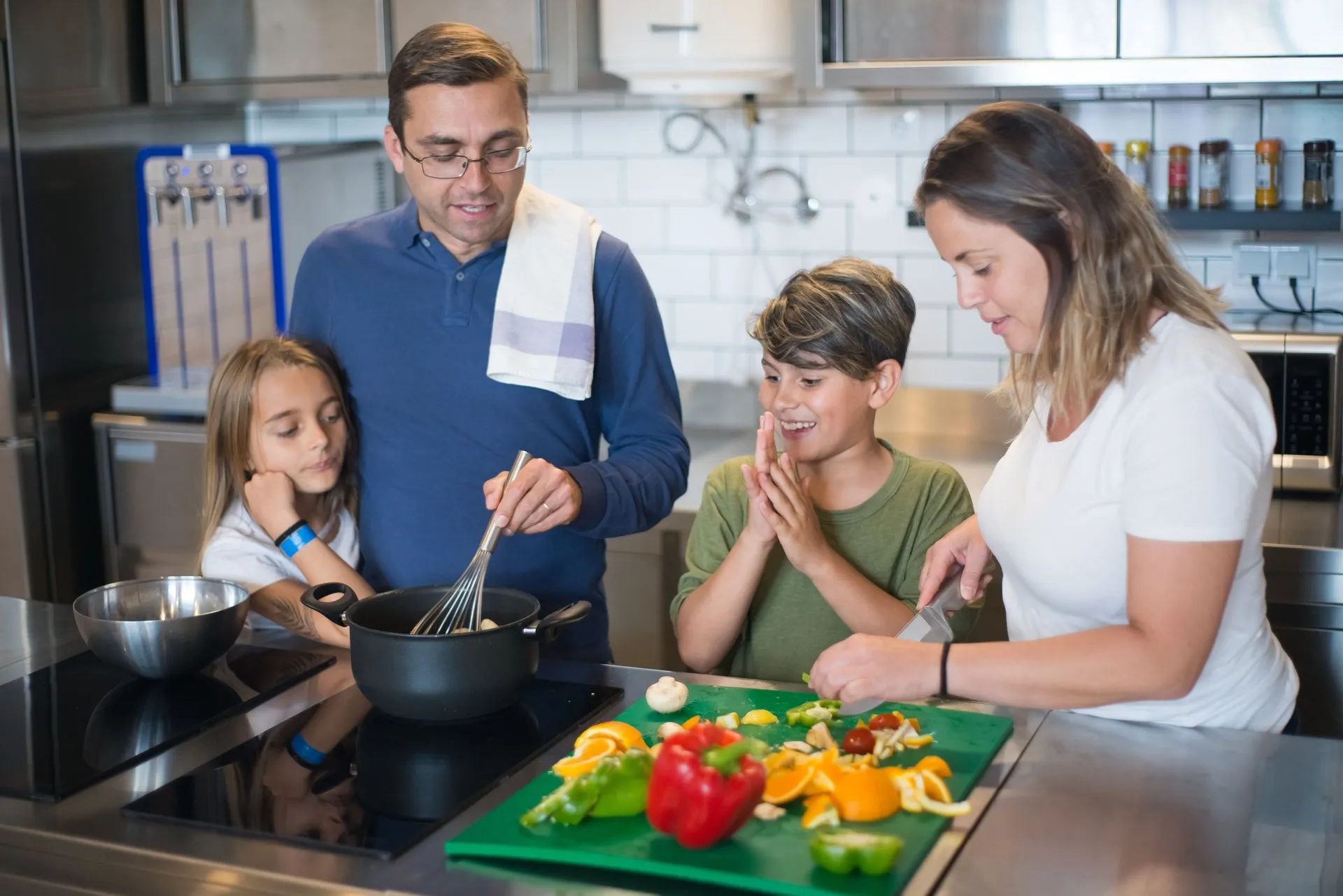 Twee volwassenen en twee kinderen bereiden samen eten in de keuken
