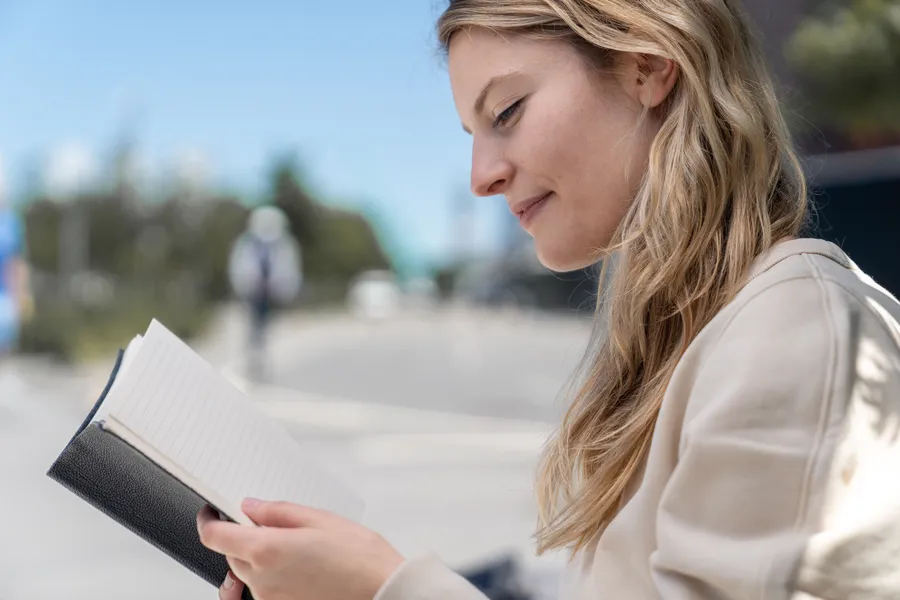 Vrouw die blij is en een boekje is aan het lezen