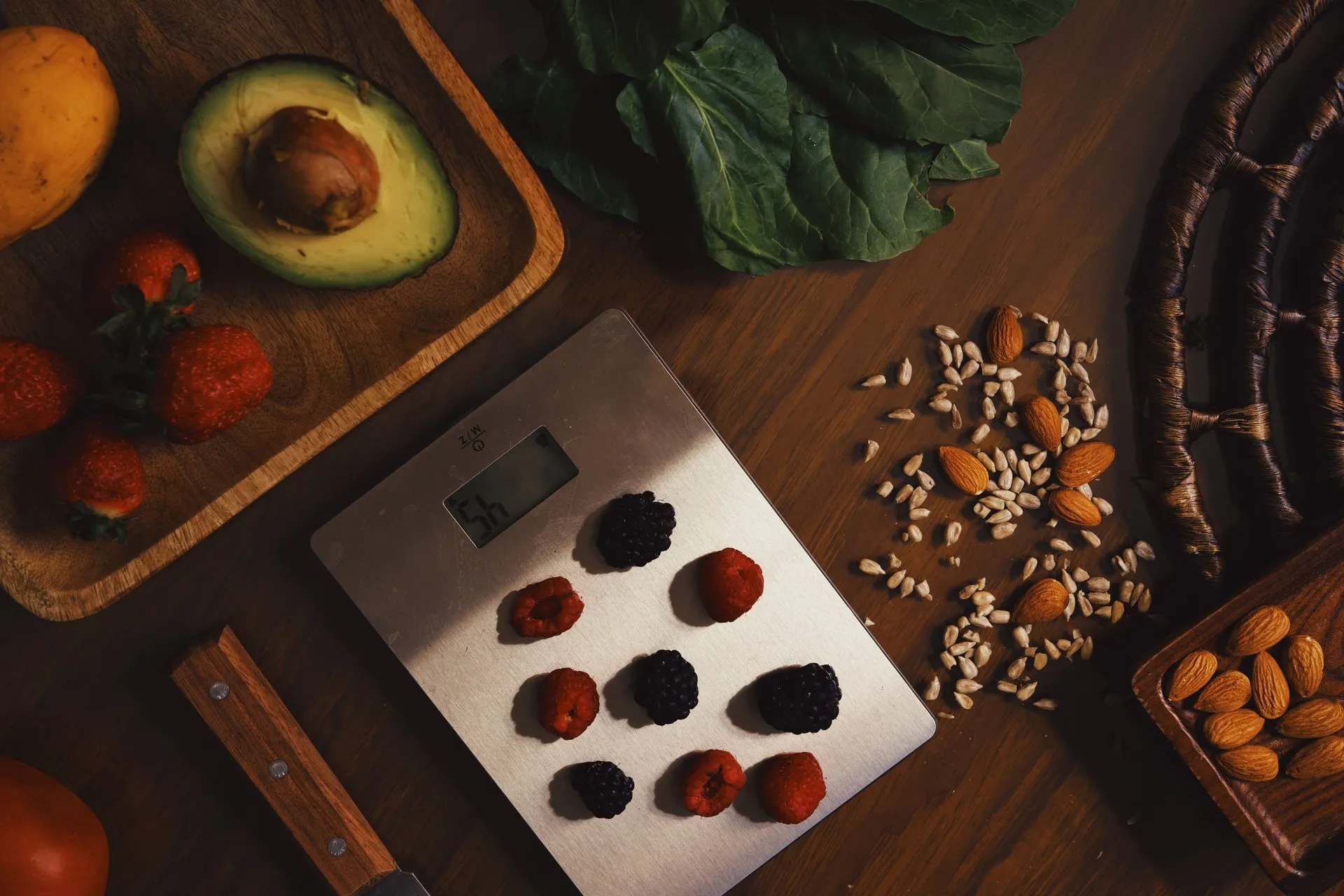 Bessen op een keukenweegschaal naast avocado, noten en bladgroenten