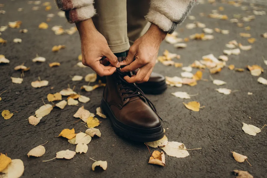 Iemand strikt schoenen op een pad met herfstbladeren