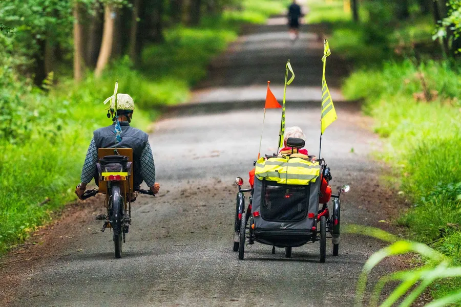Twee senioren fietsen op een bospad op een zomerse dag.