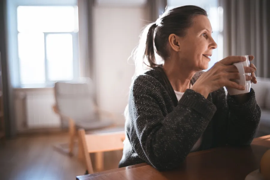 Vrouw neemt thuis een drinkpauze bij het raam