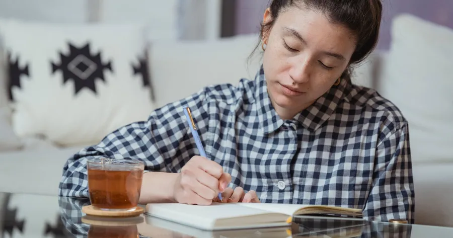 Vrouw schrijft in een notitieboek aan tafel