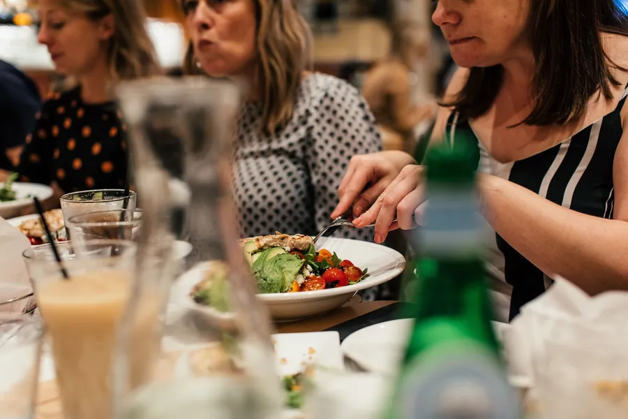 Vrouwen eten samen salade aan tafel