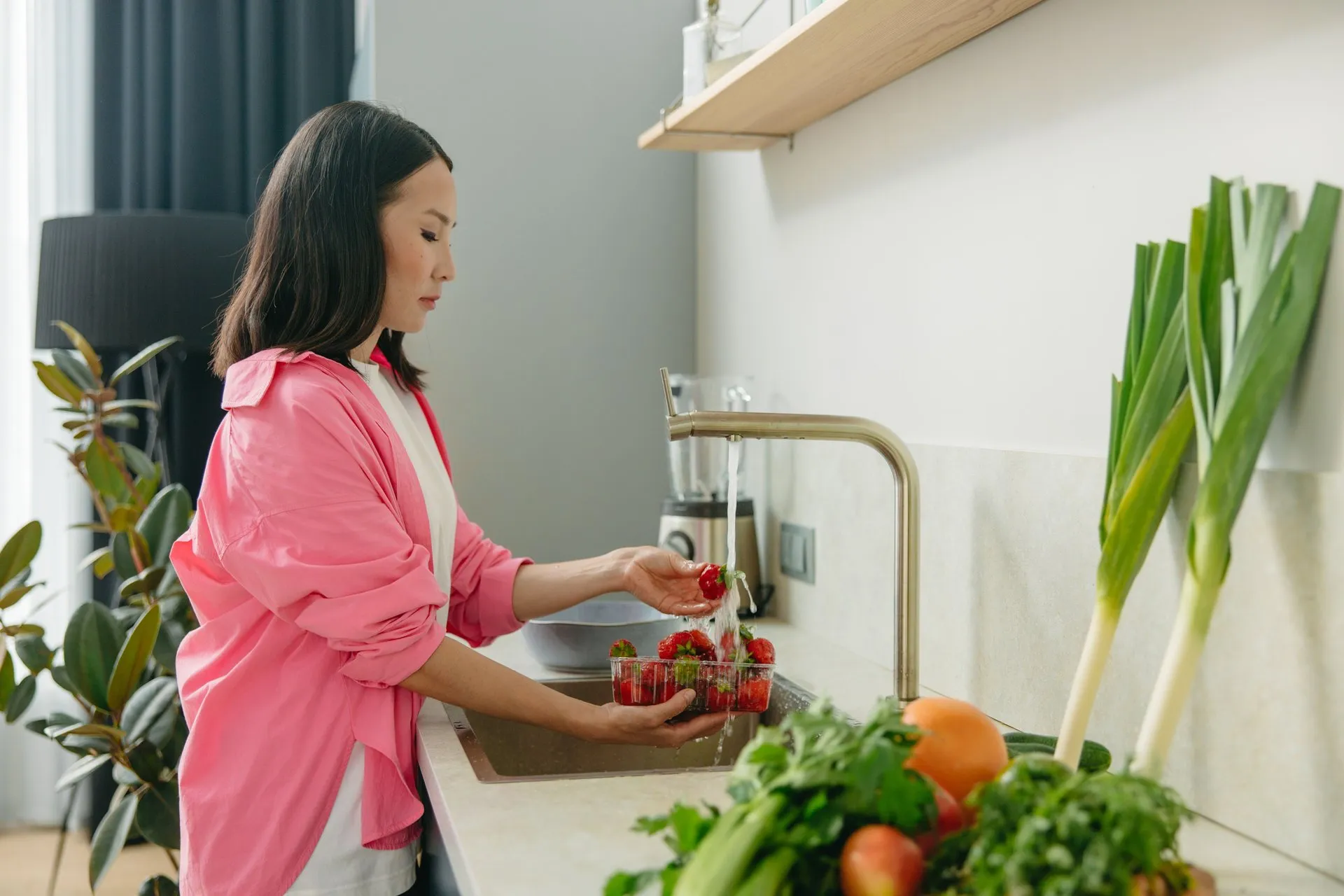 Vrouw wast aardbeien bij de gootsteen in de keuken