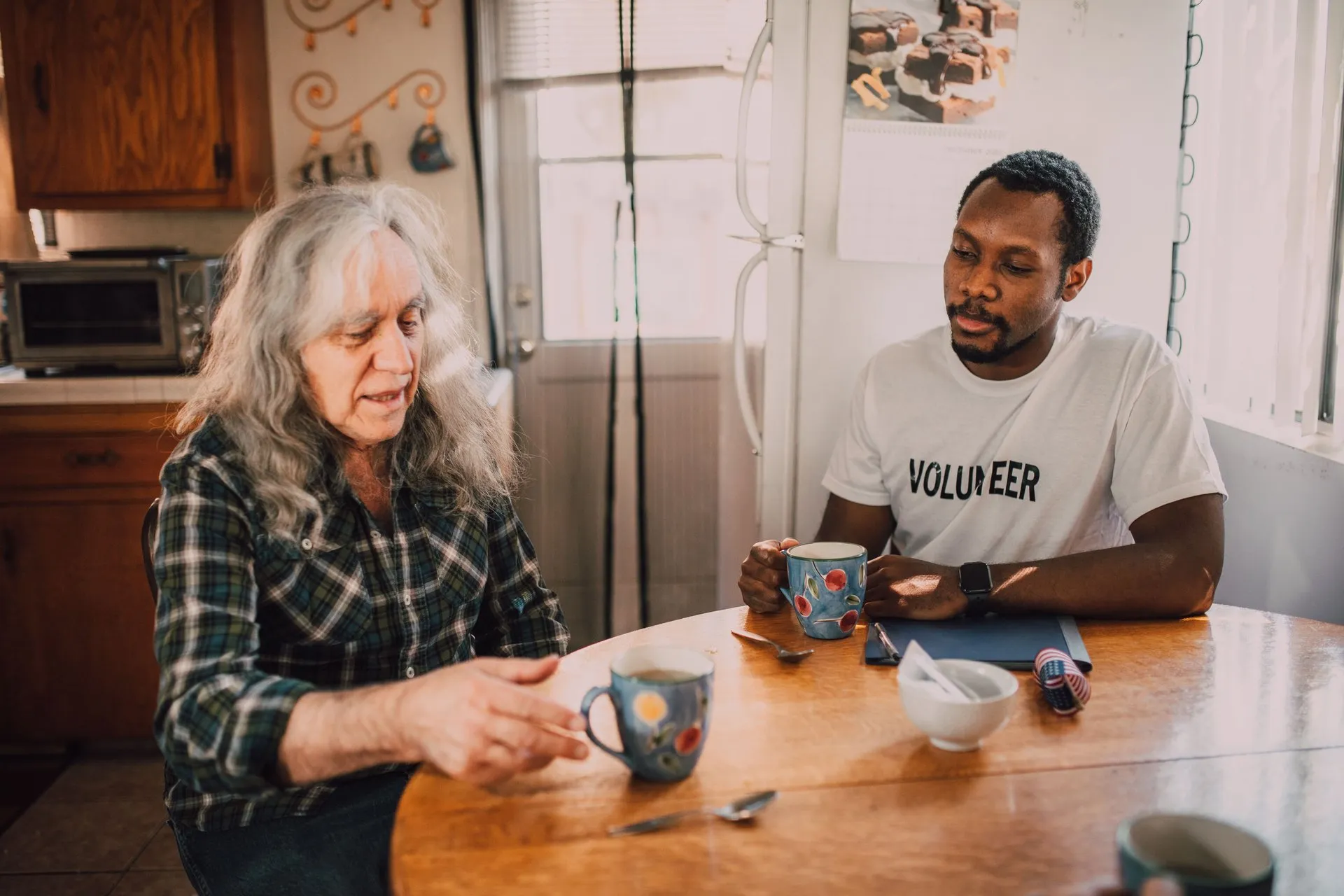 Een man en een oudere vrouw praten aan een tafel