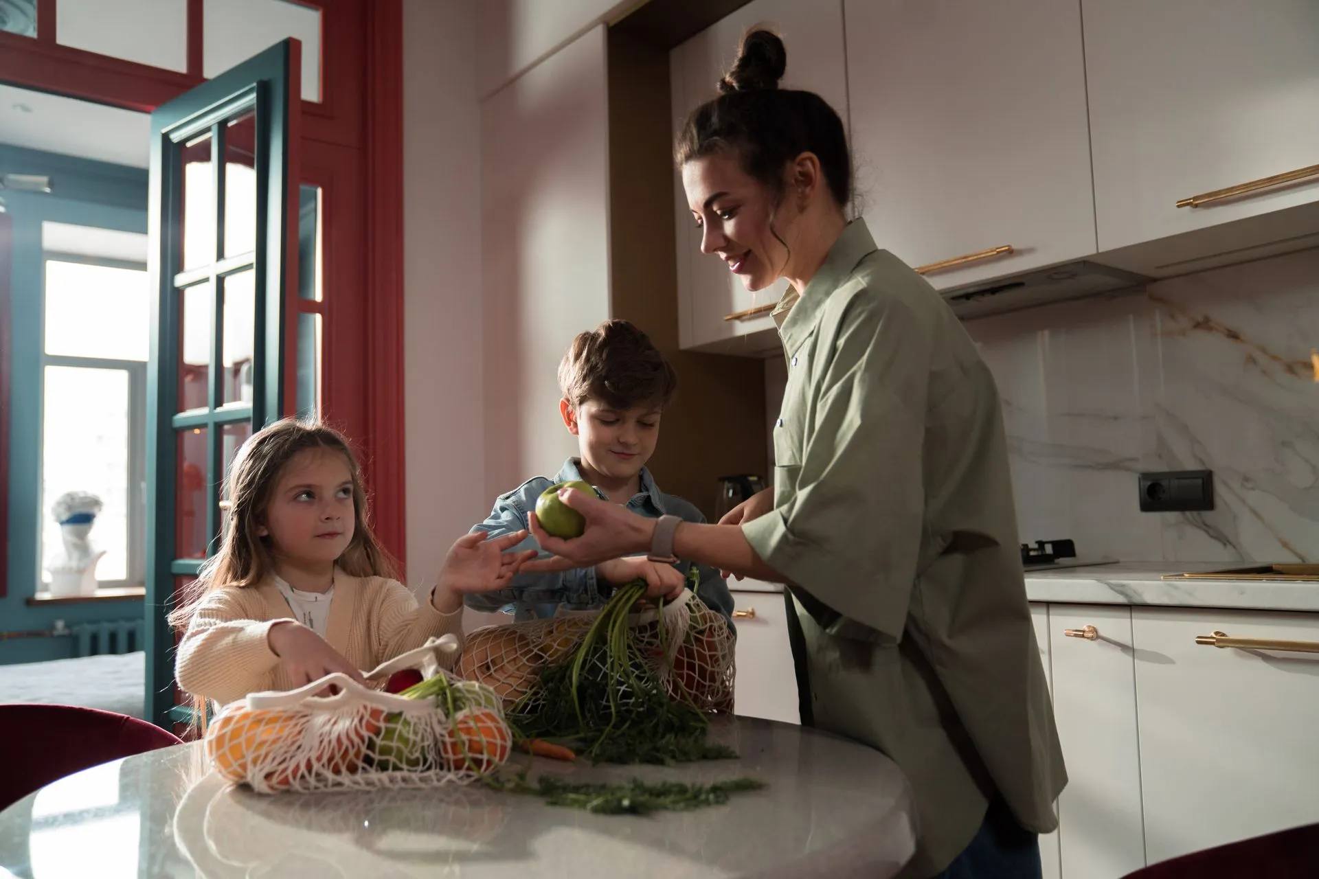 Vrouw en kinderen maken samen verse groenten klaar in een moderne keuken.