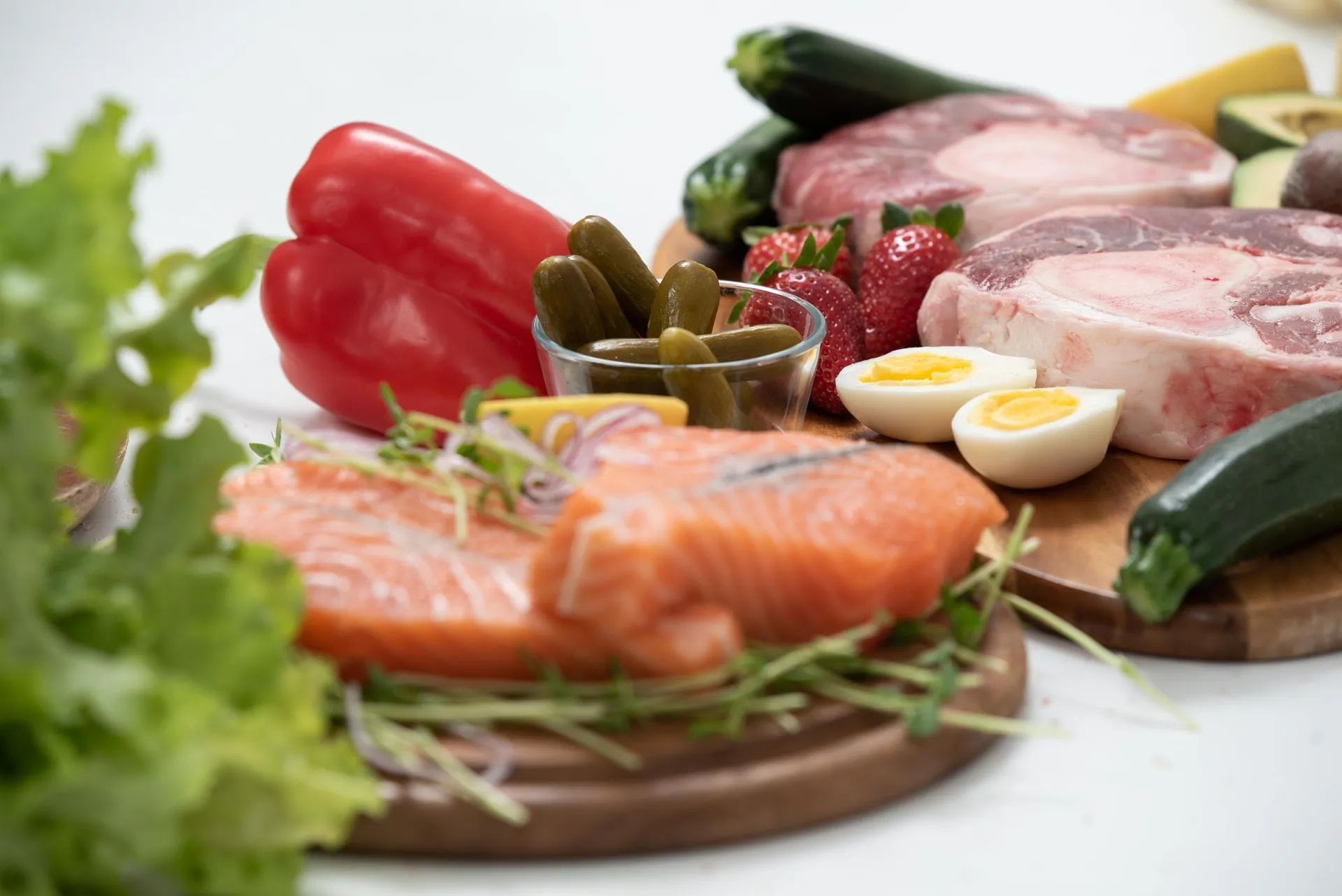 Verse zalm, eieren, groenten en fruit op een houten plank.