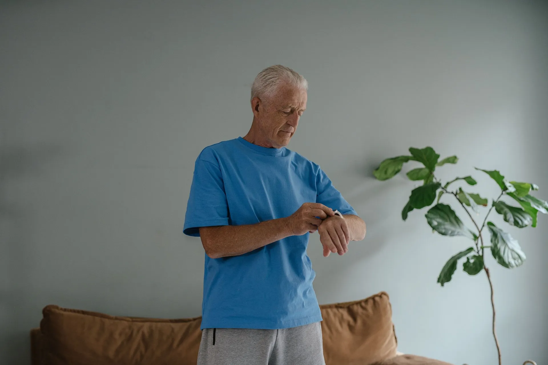Oudere man bekijkt zijn sporthorloge in de woonkamer