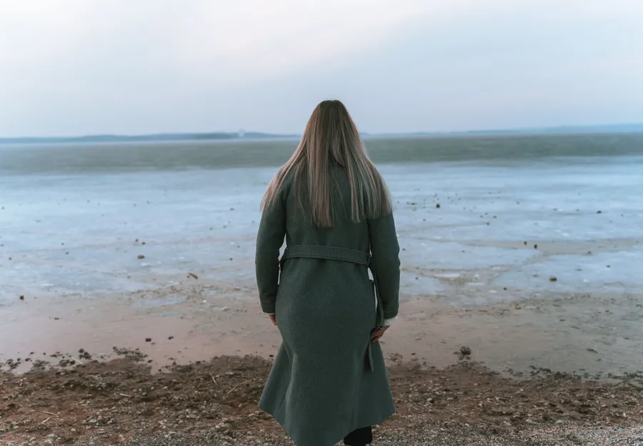 Vrouw kijkt vanaf het strand uit over het water