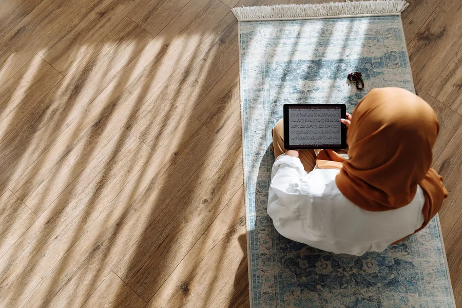 Vrouw leest op een tablet terwijl zij op een kleed zit