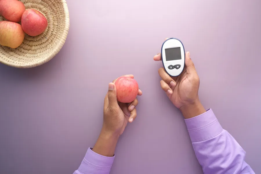 Handen houden een appel en een glucosemeter vast