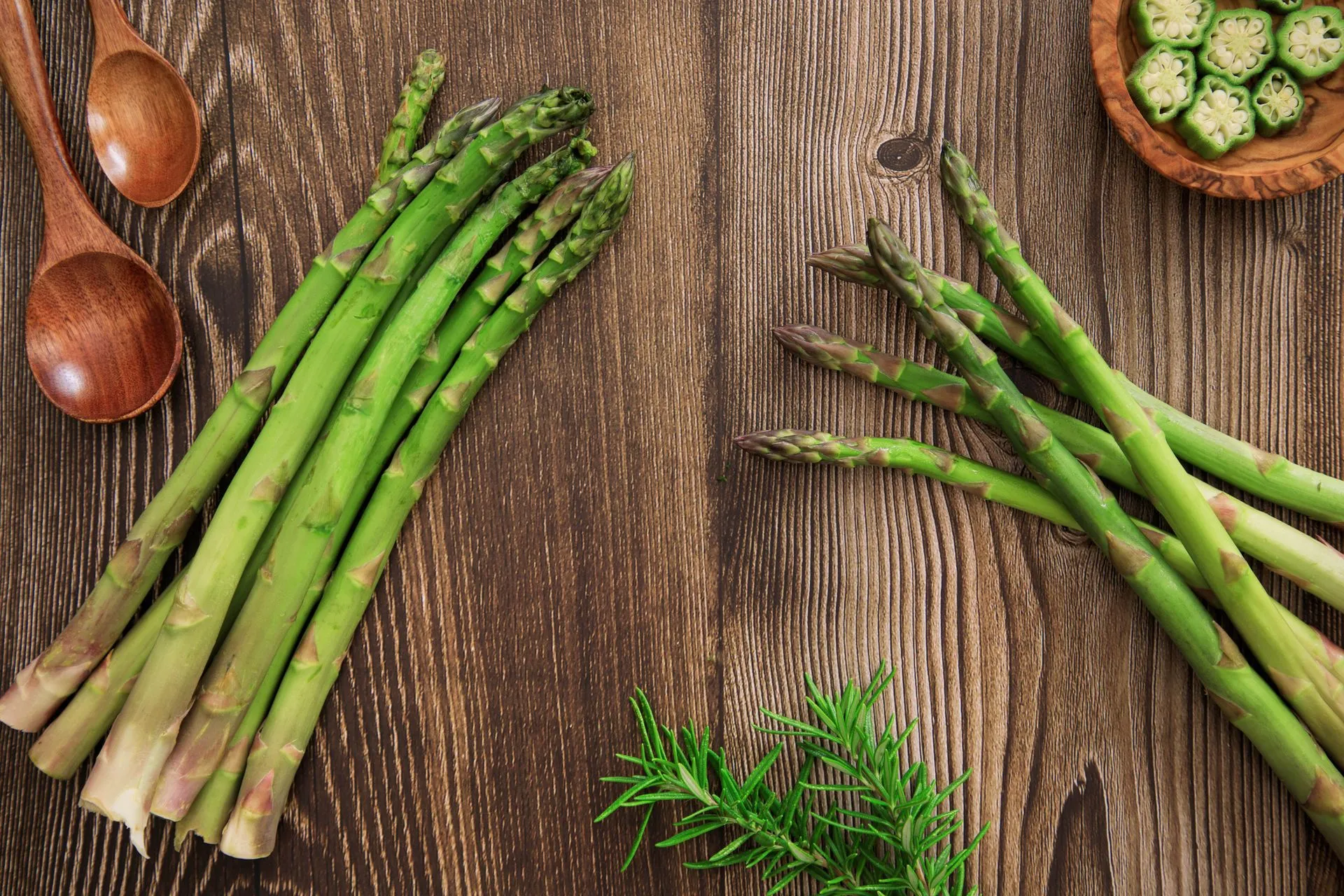 Verse asperges en kruiden op een rustieke houten tafel, van bovenaf.