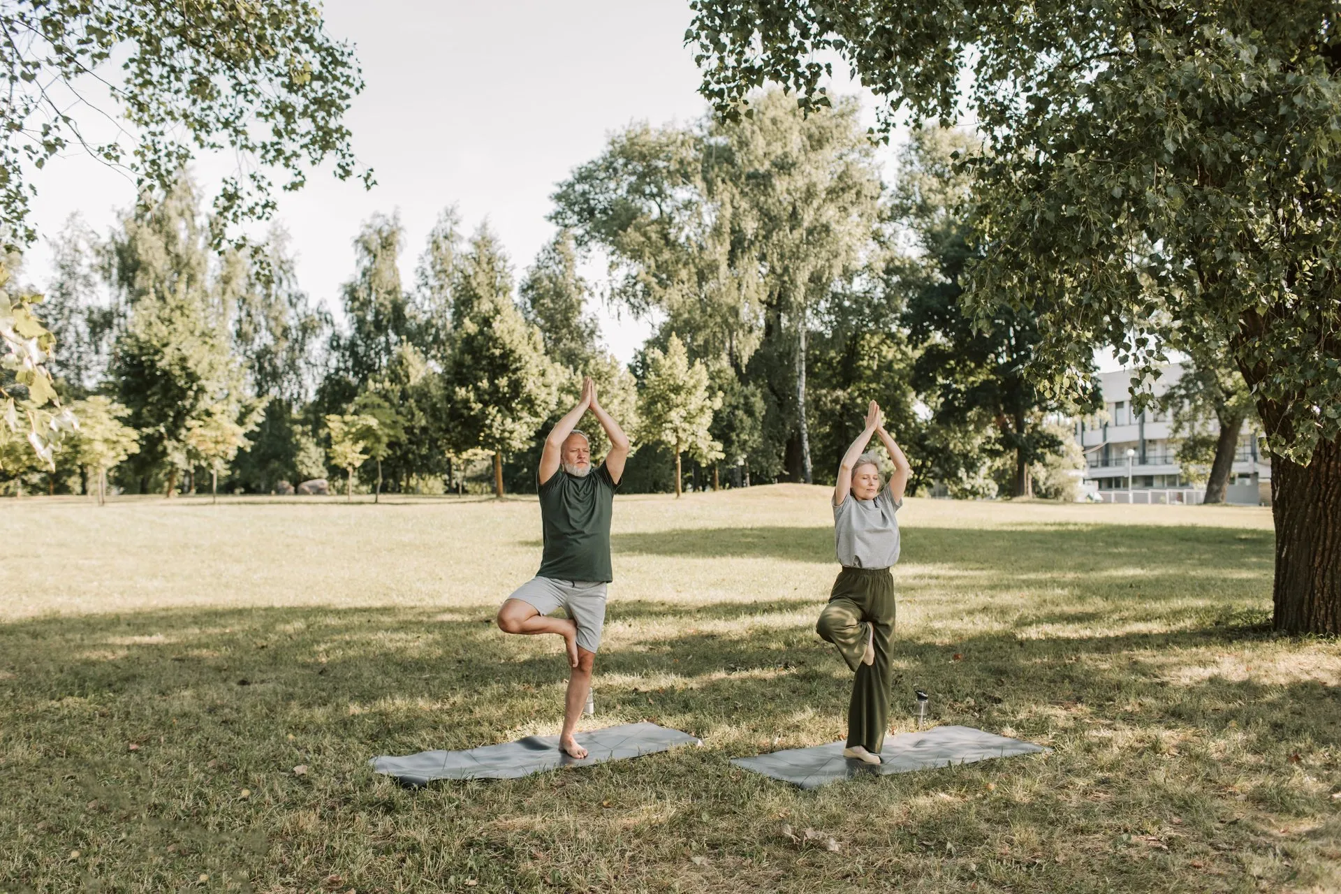 Ouder stel doet balansoefeningen op yogamatten in een park