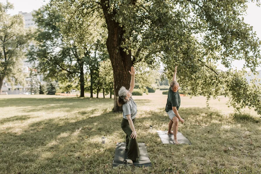 Twee oudere volwassenen doen oefeningen in een park