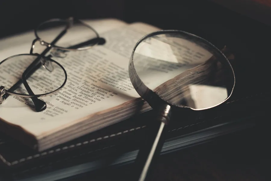 Vergrootglas en bril liggen op een opengeslagen boek