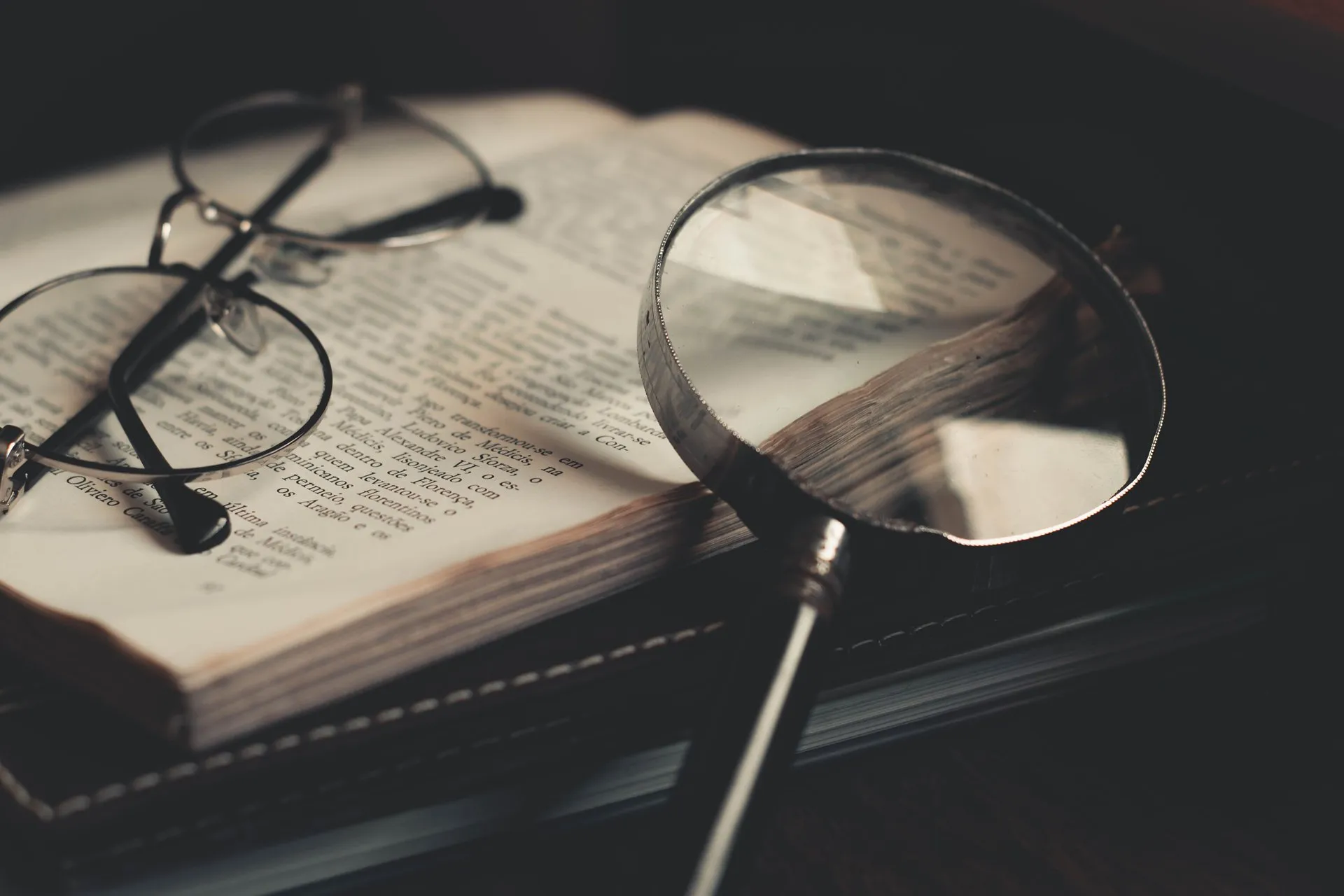 Vergrootglas en bril liggen op een opengeslagen boek