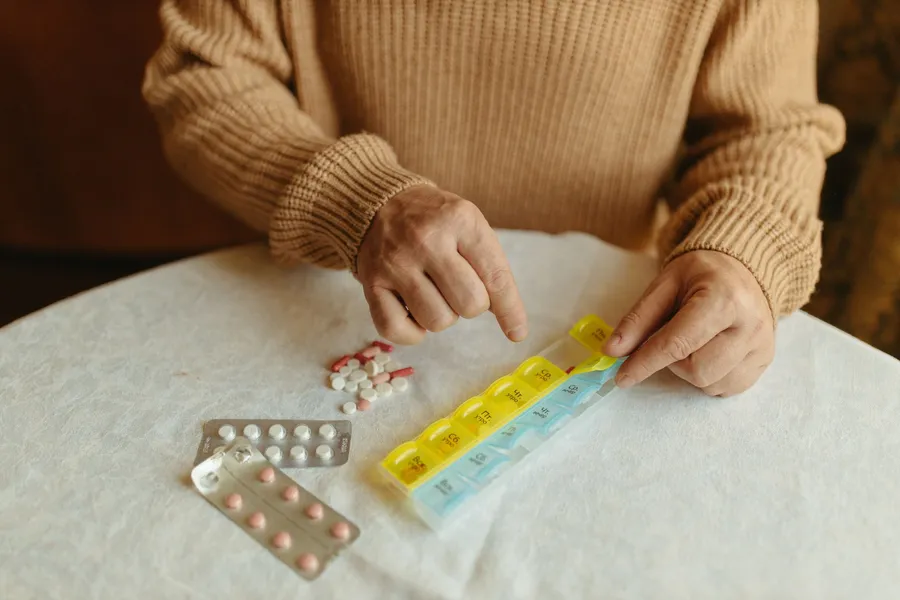 Handen verdelen medicijnen over een pillendoos