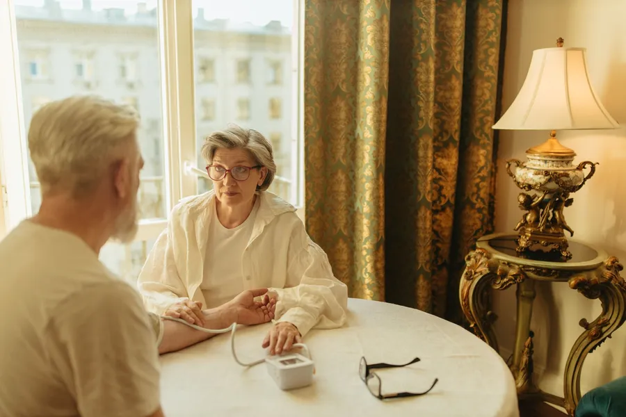Vrouw meet thuis de bloeddruk van een oudere man