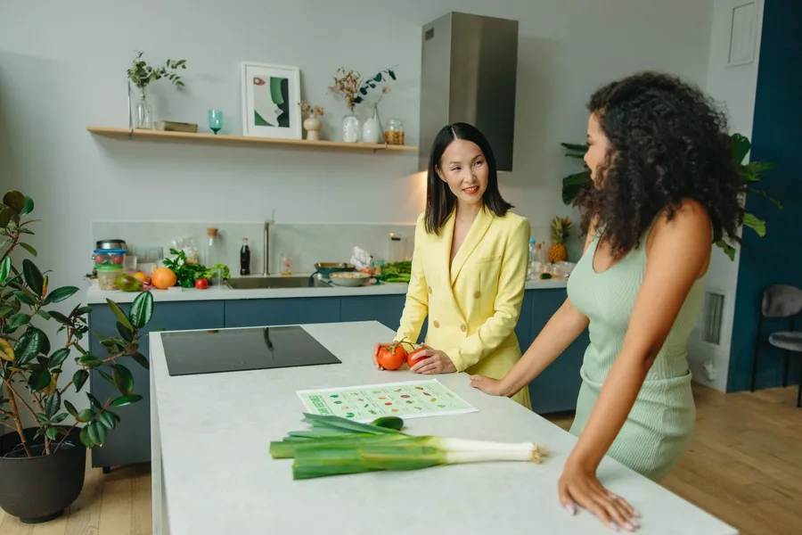 Twee vrouwen praten bij groenten en een voedingskaart