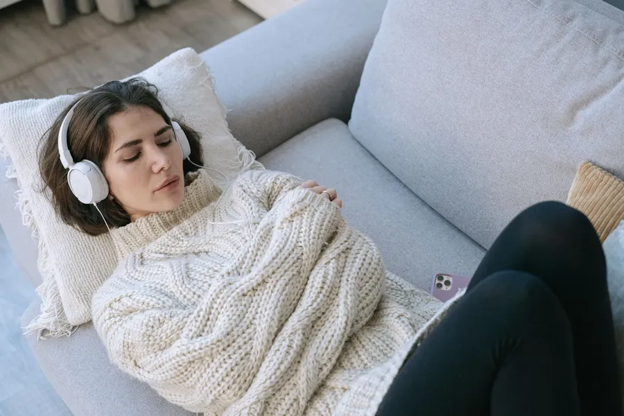 Vrouw met koptelefoon rust met gesloten ogen op de bank